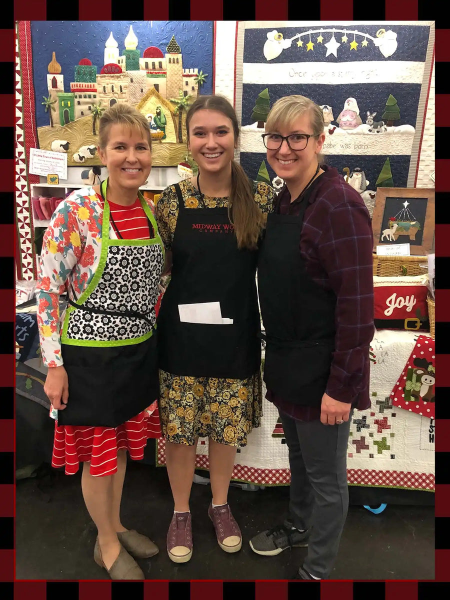 Three women wearing aprons and smiling.